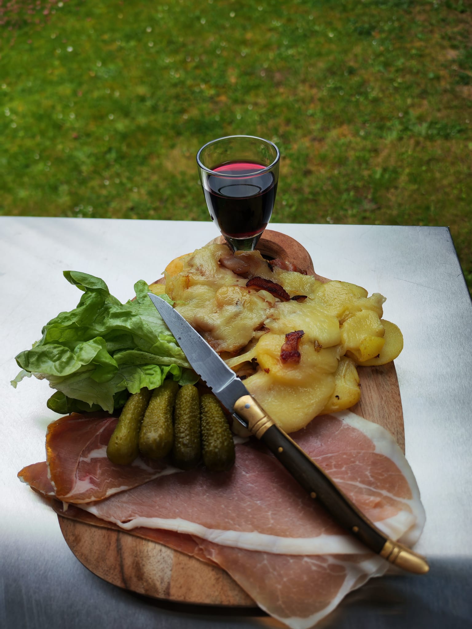 Assiette truffade dressée avec jambon sec, cornichons et verre de vin