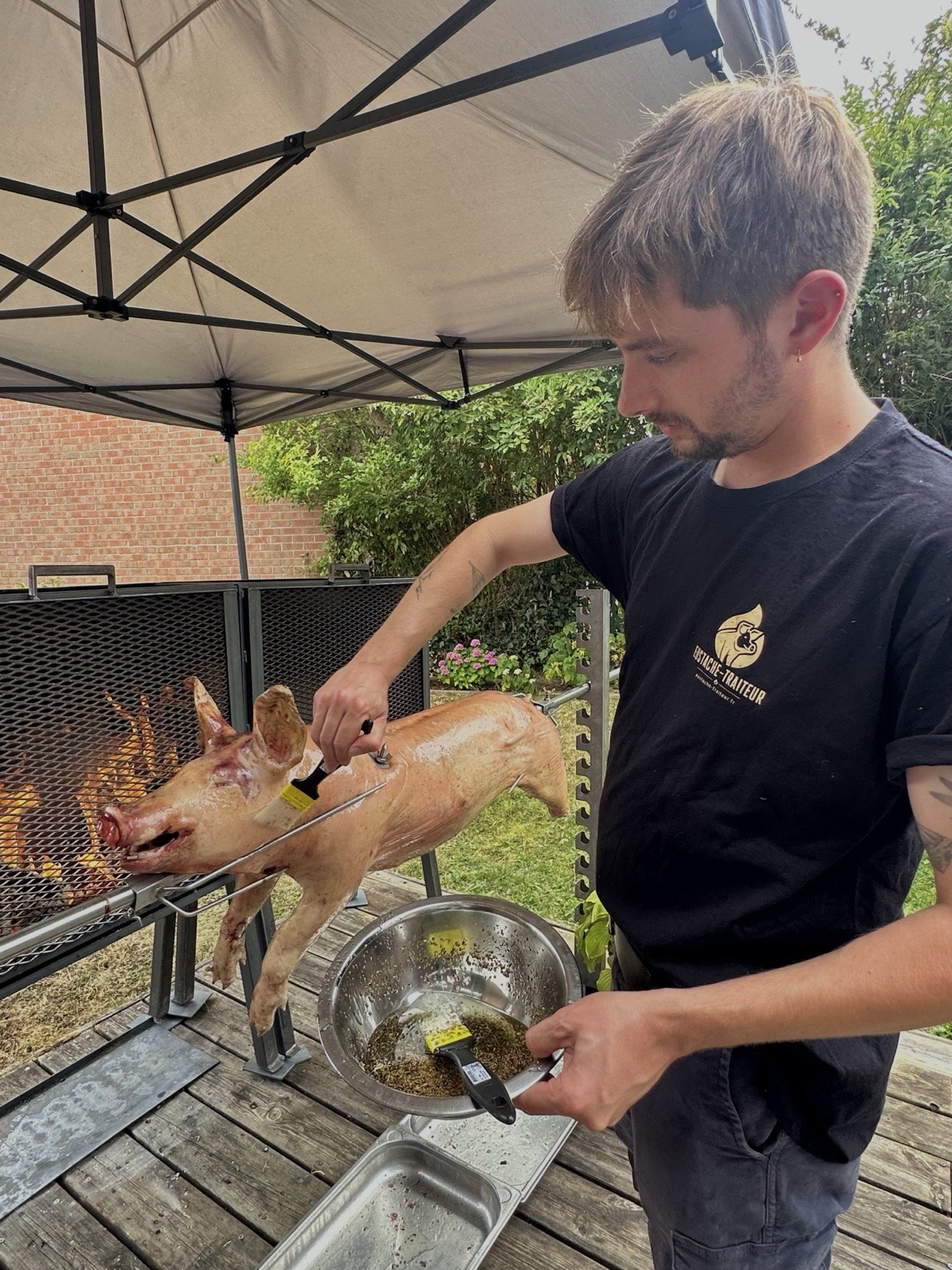 Assaisonnement du cochon à la broche pendant la cuisson