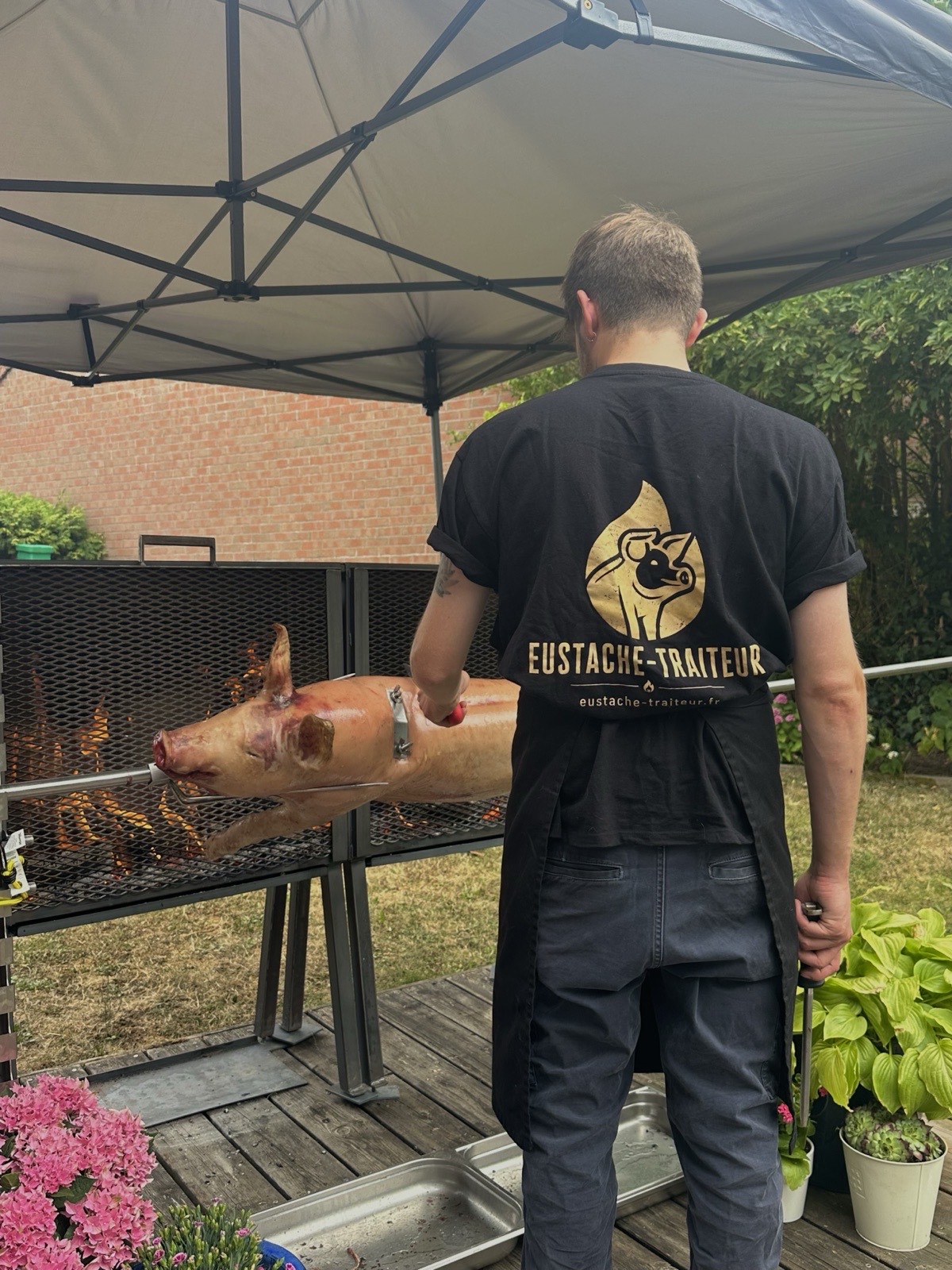 Le traiteur Eustache arrose le cochon à la broche pendant la cuisson